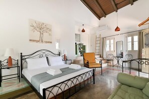 A bedroom with a bed, bedside tables, a chair, a dining area, and a kitchen. - Tepeleni Apts with Pool (Parga)