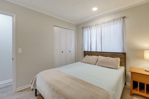 A bedroom with a bed, a wooden nightstand, a wardrobe, and a window with curtains.