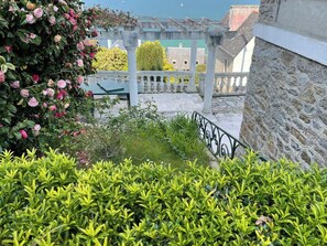 A garden with a stone wall, a metal railing, and a view of buildings in the background. - Character house facing Douarnenez bay (Douarnenez)