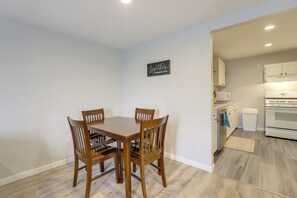 A dining area with a wooden table and chairs, a kitchen with white appliances, and a 'together' sign on the wall.