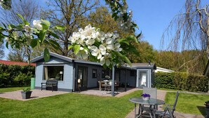 Una casa con un patio, un pequeño jardín y un árbol con flores blancas.