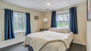 A bedroom with a bed, curtains, a nightstand, a lamp, and a window.