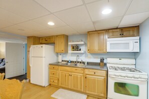 A kitchen with wooden cabinets, a refrigerator, a microwave, and a stove.