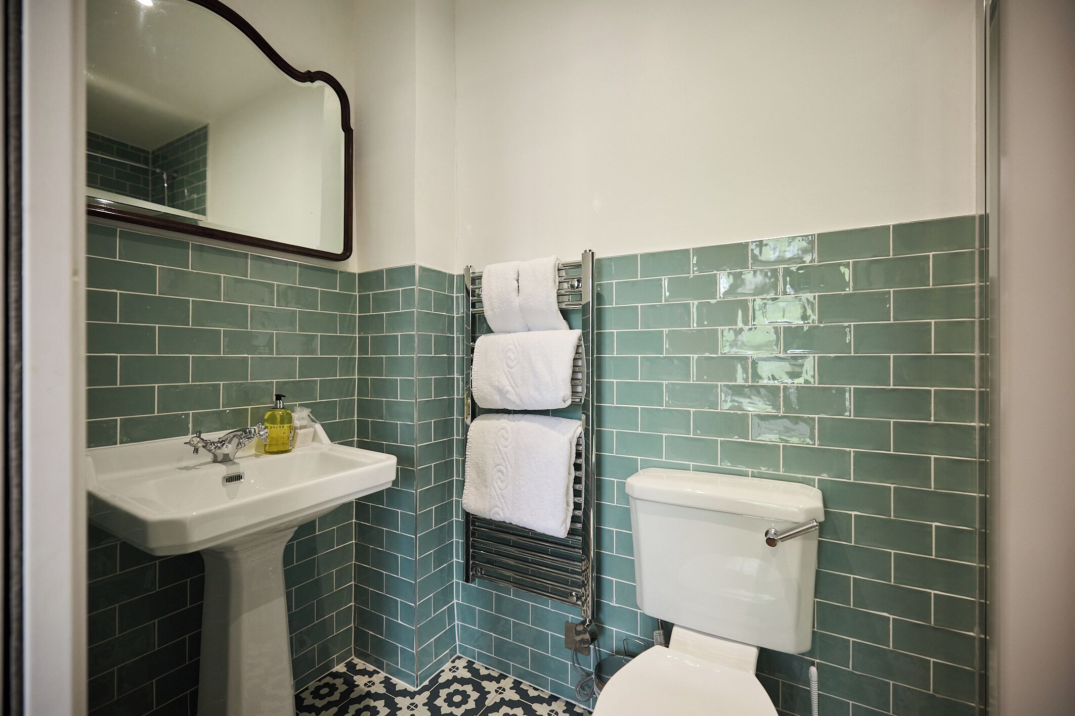 Une salle de bain équipée d’un lavabo, de toilettes et d’un porte-serviettes.