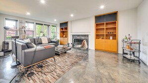 Un salon moderne avec un canapé, une cheminée, des étagères en bois et une table basse.