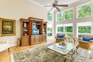 A spacious living room with a large window, a ceiling fan, and a wooden entertainment center. - Group-Friendly Mtn Estate 2 Mi to Dtwn Waynesville (Waynesville)