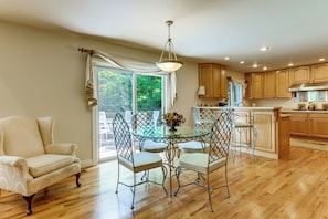 A kitchen with wooden cabinets, a dining table with chairs, and a large window with curtains. - Group-Friendly Mtn Estate 2 Mi to Dtwn Waynesville (Waynesville)
