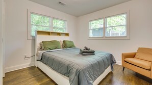 Une chambre à coucher avec un lit, une chaise et deux fenêtres équipées de stores.
