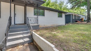 Une maison de plain-pied avec un porche à l’avant, une porte bien visible et un petit jardin devant.
