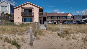 A beachfront property with a two-story building, a covered walkway, and a parking area. - Beachfront Condotel  on OOB, Steps From Downtown (Old Orchard Beach)