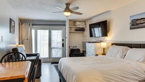 A hotel room with a bed, a dining table, chairs, a ceiling fan, a TV, and a view of the outdoors. - Beachfront Condotel  on OOB, Steps From Downtown (Old Orchard Beach)
