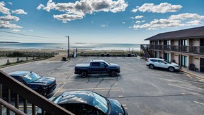 A parking lot with a building, a view of the ocean, and a clear sky. - Beachfront Condotel  on OOB, Steps From Downtown (Old Orchard Beach)
