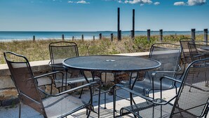 A metal table and chairs set on a patio overlooking the beach. - Beachfront Condotel  on OOB, Steps From Downtown (Old Orchard Beach)