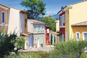 A narrow street with colorful buildings, a clear sky, and a mountain in the background. - Village Duplex for 8 with Spa, Fayence (Fayence)