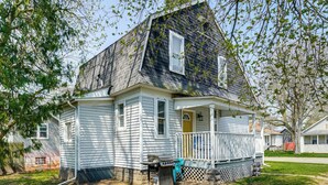 A two-story house with a porch, a grill, and a fenced yard. - Gateway to Dtwn Port Huron & Lake! Cozy Home (Port Huron)