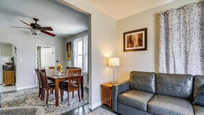 A living room with a sofa, a dining table with chairs, a ceiling fan, and a lamp. - Gateway to Dtwn Port Huron & Lake! Cozy Home (Port Huron)
