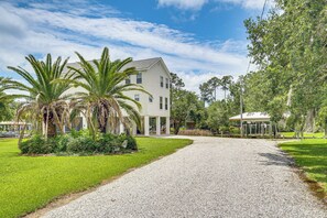 A house with a gravel driveway, palm trees, and a covered structure.