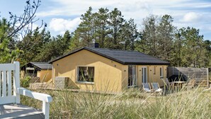 A single-story house with a flat roof, a chimney, and a small porch with two chairs. - Stone house's simplicity in Jerup's vicinity (Jerup)