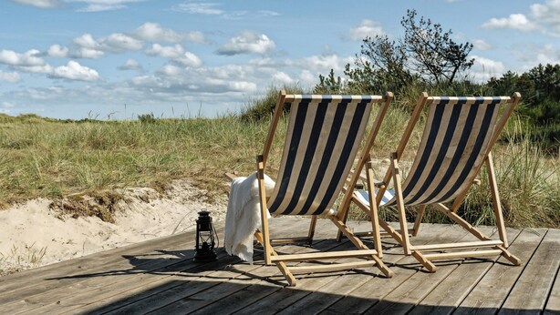 Two striped beach chairs on a wooden deck with a sandy beach and grassy dunes in the background. - Stone house's simplicity in Jerup's vicinity (Jerup)