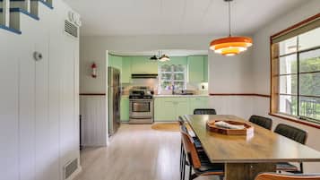 A kitchen with a dining area, a stove, refrigerator, and a window with a view.