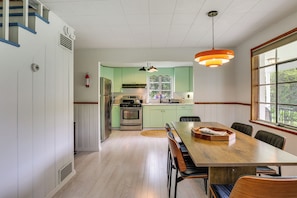 A kitchen with a dining area, a stove, refrigerator, and a window with a view.