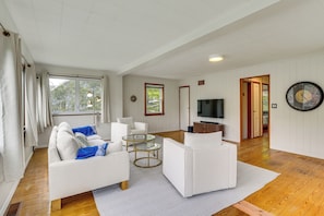 A spacious living room with a white sofa, a coffee table, and a television.