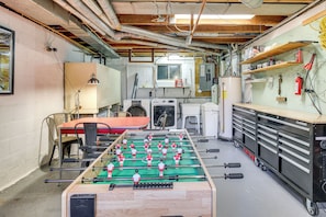 A room with a foosball table, a washing machine, and a utility cart.