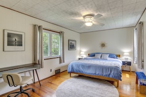 A bedroom with a bed, desk, chair, ceiling fan, and two bedside lamps.