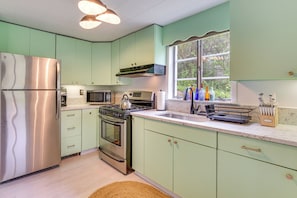 A kitchen with stainless steel appliances, a window with a view, and a countertop with utensils.