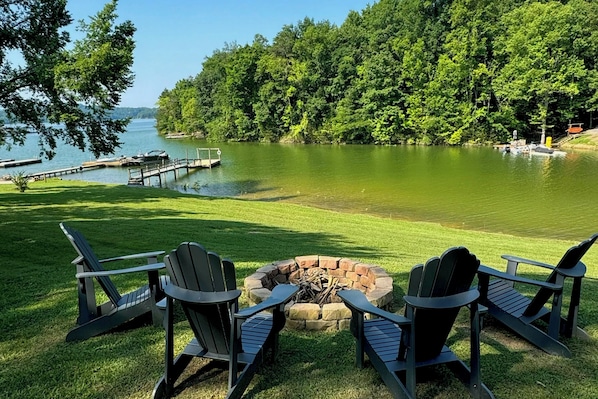 Vista del lago con una fogata y sillas Adirondack.