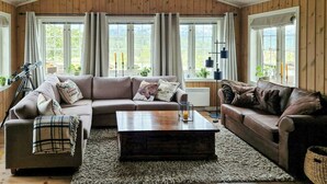 A cozy living room with a wooden ceiling, large windows, a telescope, and a fireplace. - Log cabin with hot tub in Rauland (Telemark)