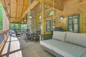 Eine Holzhütte mit einer Terrasse, einer Couch und einem Esstisch.