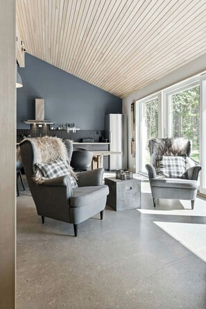 A modern living room with two grey armchairs, a coffee table, and a kitchen in the background. - Historic cabin idyll by Espedalsvannet (Espedalen)