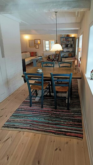A dining area with a wooden table, blue chairs, and a colorful rug.