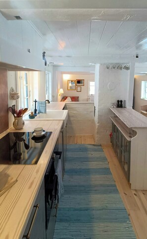 Una cocina moderna con encimeras de madera, una alfombra azul y vistas al salón.