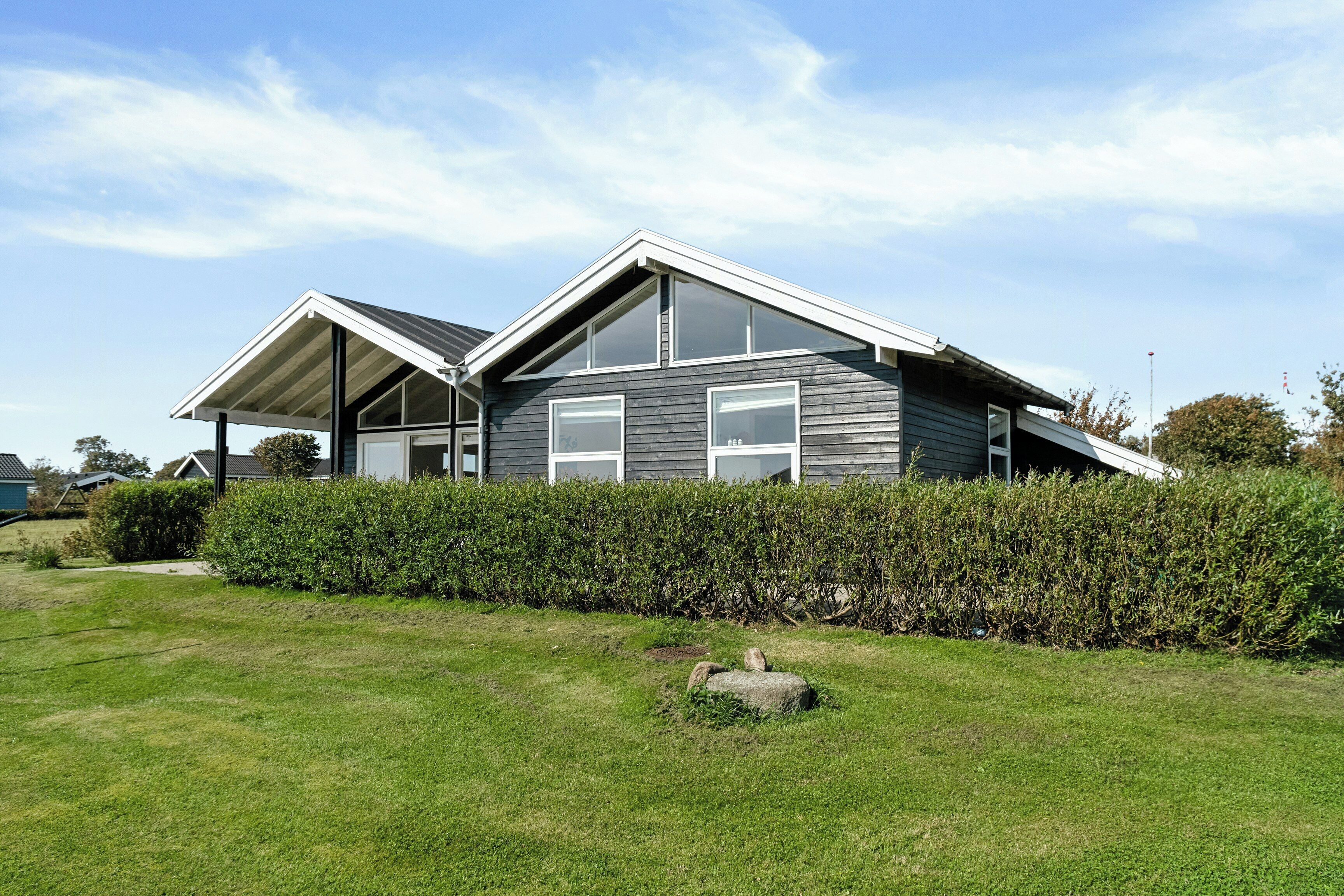 A modern house with a sloped roof, large windows, and a well-maintained lawn.