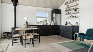 A modern kitchen with a central island, black cabinets, and a built-in stove. - Cozy home by Limfjord with bathing jetty (Snedsted)