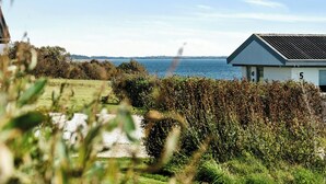 A coastal property with a view of the sea, a white building with a grey roof, and a gravel path leading to the entrance. - Cozy home by Limfjord with bathing jetty (Snedsted)