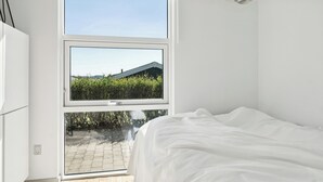A bedroom with a bed, a window, and a ceiling light fixture. - Cozy home by Limfjord with bathing jetty (Snedsted)