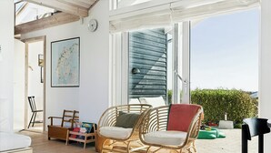 A bright room with a wooden floor, wicker chairs, a map on the wall, and a large window. - Cozy home by Limfjord with bathing jetty (Snedsted)