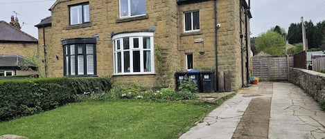 A stone house with a garden, a paved pathway, and a fence.