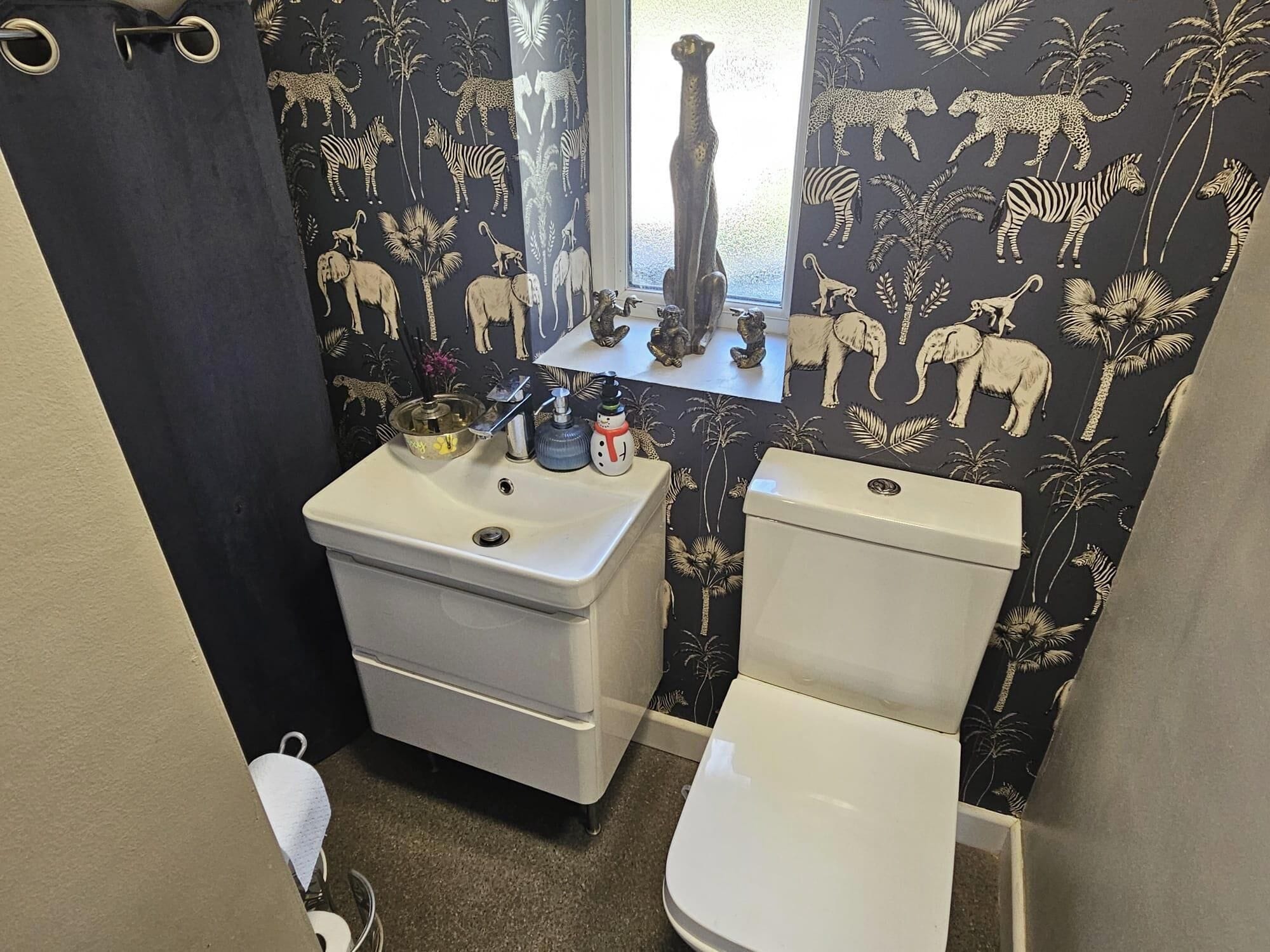 A bathroom with a toilet, sink, and decorative items on the wall.