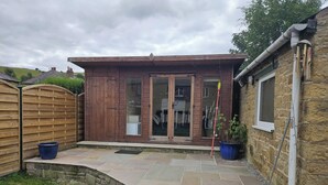 A wooden building with a glass door, a stone wall, and a small window. - Tranquil Hope Valley Retreat With 3 Bedrooms (Hope Valley)