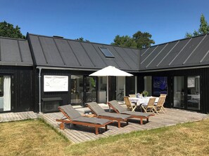 A modern house with a deck, lounge chairs, and a table with umbrellas. - Modern house in Munkerup near Gilleleje (Gilleleje)