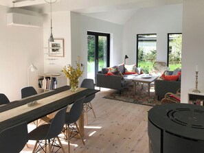 Ein modernes Wohnzimmer mit Essbereich, großen Fenstern und Blick auf Grünflächen.