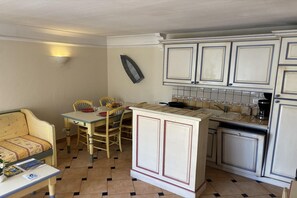Une cuisine compacte dotée d’un coin repas, comprenant une petite table, des chaises et un îlot central intégré avec un évier.