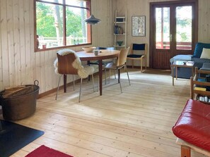 Ein gemütliches Blockhaus-Interieur mit einem Holzespeisetisch, Stühlen, einer Couch und einem Kamin.
