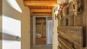 Un couloir en bois avec une porte rustique, un lit en arrière-plan et un escalier.