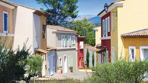 Una calle estrecha con edificios coloridos, cielo despejado y una montaña al fondo.