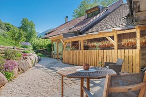 Un espace extérieur aménagé en bois avec une table et des chaises, un patio couvert et une vue sur une montagne.